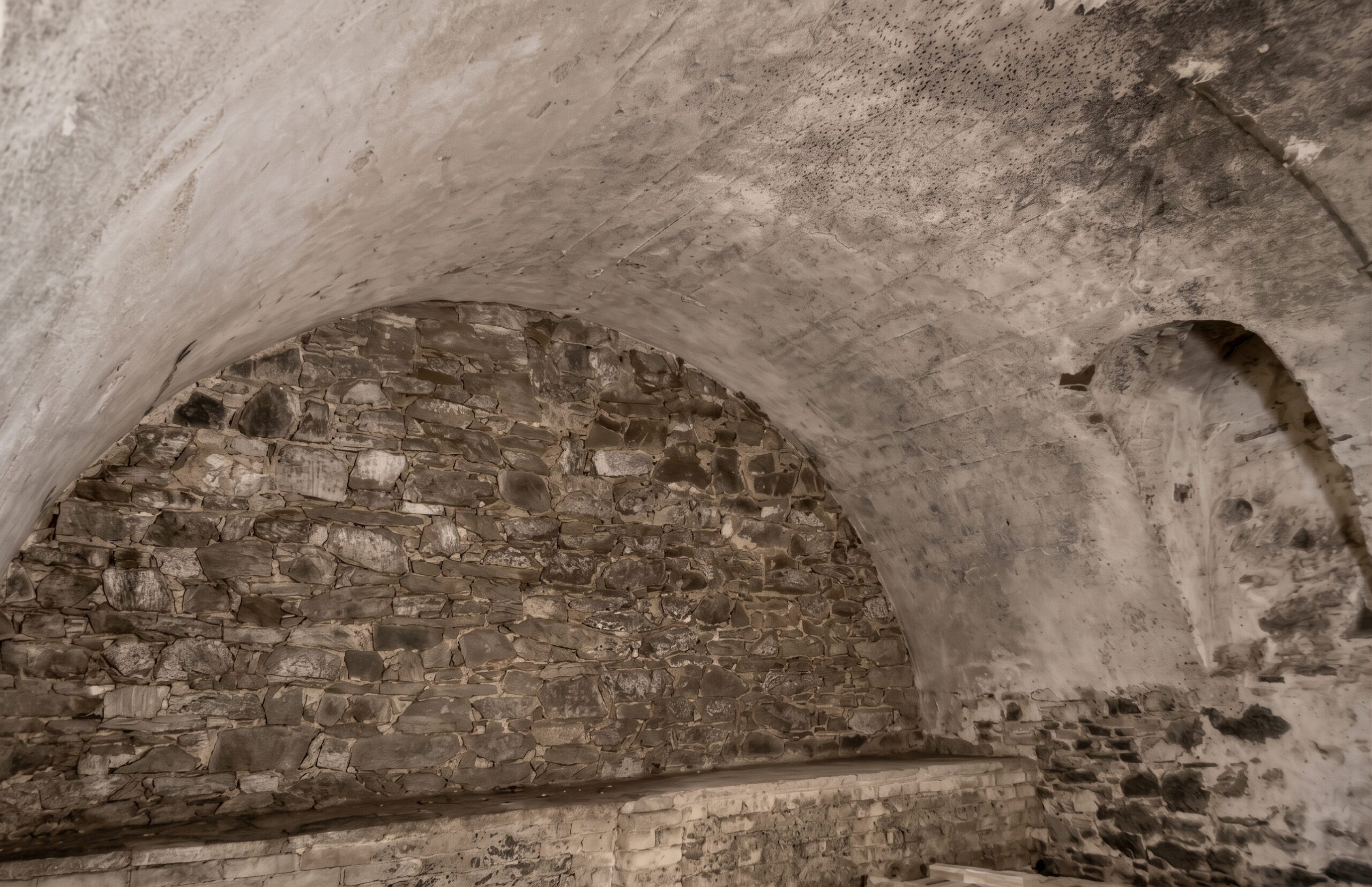 Vor Beginn der Altstadtsanierung spiegelten die Kellersysteme der Häuser Gemüsegasse 12-14 und Mehlgasse 15 eine für Koblenz typische Situation wider: Die ursprünglichen Bruchsteingewölbe wurden aus Luftschutzgründen mit Beton stabilisiert und damit so entstellt dass Detailuntersuchungen zur Ergründung der Baugeschichte - wenn überhaupt - nur noch begrenzt möglich sind. Das Originalfoto von Herbert Gauls entstand im Rahmen der Bestandsaufnahmen (1977) und war in der Printversion der Dissertation abgedruckt. Für das Internet wurde es mit KI leicht überarbeitet.